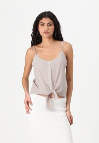 Top de tirantes a rayas en colores claros, con botones en el frente y un dobladillo anudado; combinado con una falda blanca texturizada.