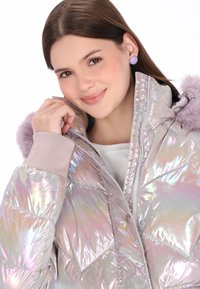 Perłowa kurtka puchowa z zamkiem z przodu, pluszowym lawendowym obszyciem kaptura i beżowymi mankietami. Gładka, lśniąca tekstura z przeszyciami w kształcie diamentu.