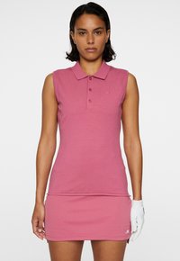 Rosa ärmlös golfpolo med krage, tre framknappar, texturerat tyg och en logotyp på bröstet, i kombination med en matchande mini-skjorta.