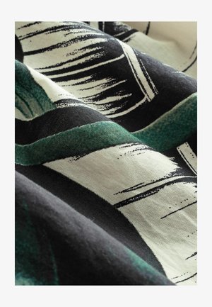 Abstrakter Stoff mit kräftigen grünen und schwarzen Mustern auf einem hellen Hintergrund, der eine weiche Textur und geschwungene Formen aufweist.