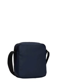 Granatowa torba na ramię wykonana z gładkiego materiału, w kształcie kwadratu, z zamkiem błyskawicznym i trwałym, czarnym, regulowanym paskiem.