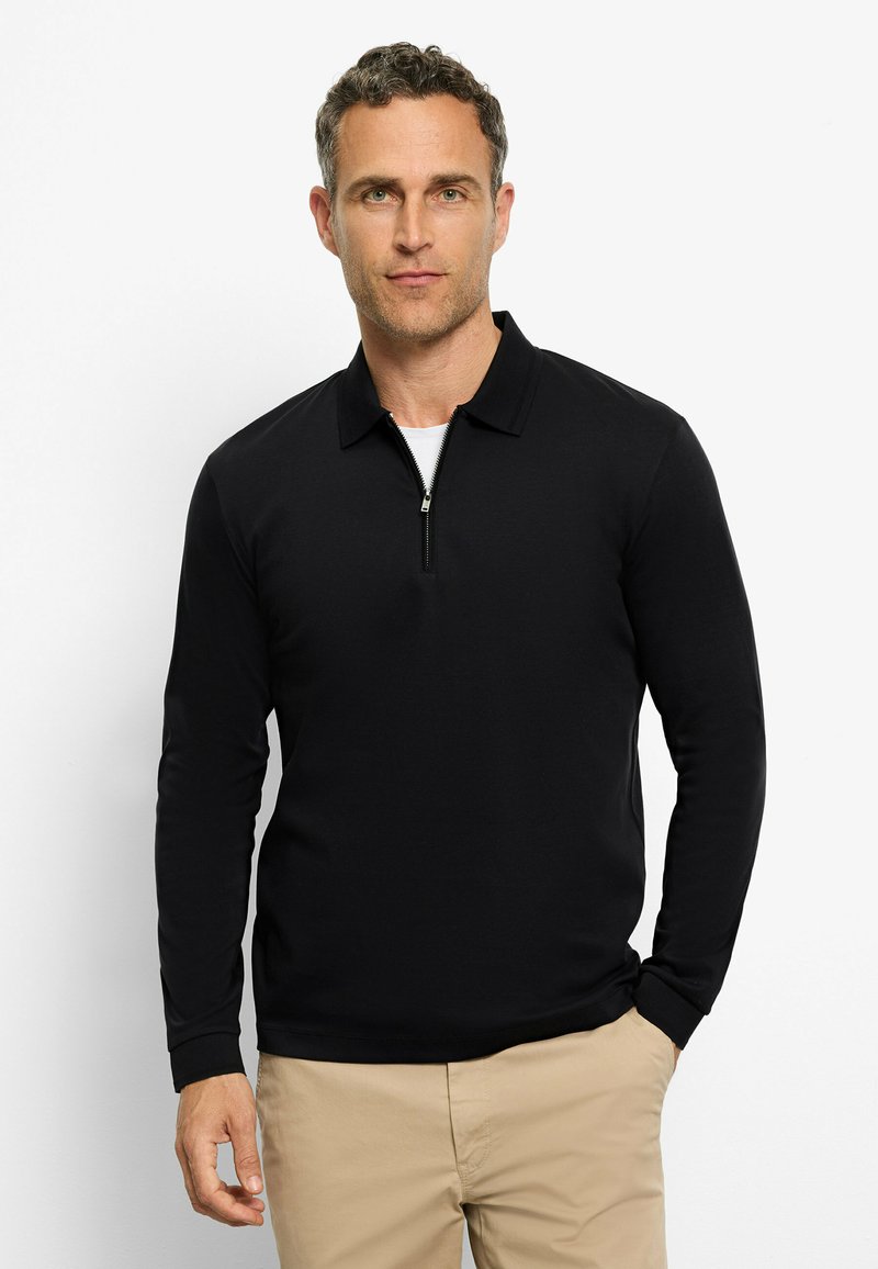 Zwarte polo-shirt met lange mouwen en een ritskraag. Gemaakt van een soepele stof, heeft het een getailleerd ontwerp en manchet-mouwen.