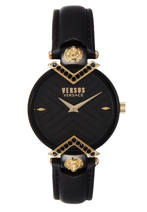 Reloj con correa de cuero negra, esfera redonda negra y dorada, agujas doradas, detalles con cabeza de león y logotipo "Versus Versace" en la esfera.
