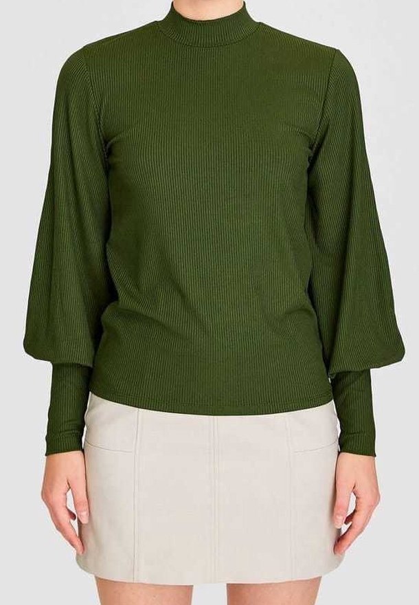 Top de mangas largas de canalé verde oscuro con un cuello alto y mangas abullonadas, combinado con una mini falda beige claro con costuras frontales.