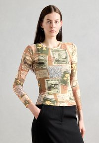 Long-sleeve shirt with a vintage postcard print in earthy tones. Features a fitted shape and round neckline, paired with black trousers.