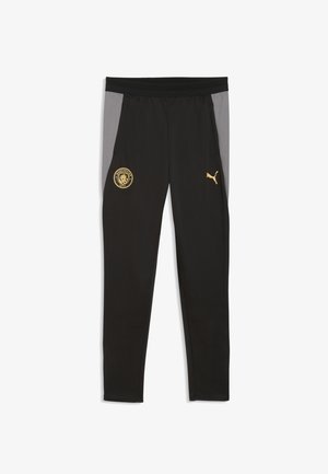 Czarne spodnie sportowe z szarymi panelami bocznymi, z złotym logo Manchester City po lewej stronie i złotym logo Puma na prawej udzie.