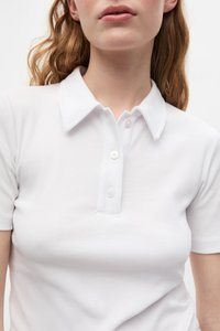 Polo alb cu dungi, cu guler ascuțit și închidere cu trei butoane, având un design ajustat și o textură de țesătură netedă.