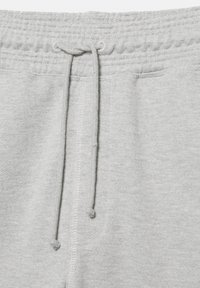 Hellgraue Sweatpants mit elastischem Bund, sichtbarem Tunnelzugknoten, zentraler Naht und teilweise vorne auf beiden Seiten eingesetzten Taschen.