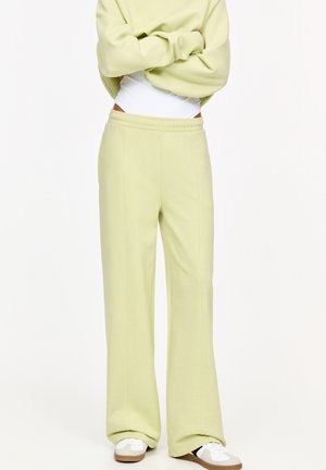 Light green jogger pants made of soft fabric, featuring a relaxed fit, elastic waistband, and wide legs. Paired with white sneakers.