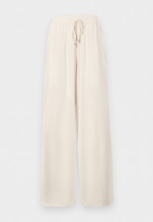 Pantalon ample de couleur crème avec ceinture élastique et cordon de serrage, fabriqué en tissu léger.