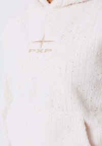 Sudadera blanca con tejido texturizado, que cuenta con pequeñas motas y un logo "PXP" beige en la parte frontal. Incluye un bolsillo tipo canguro.