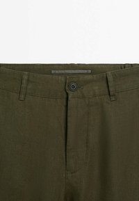 Pantaloni in lino verde oliva con cintura, chiusura a bottone e fronte piatto. Il tessuto presenta una texture sottile con una finitura liscia.