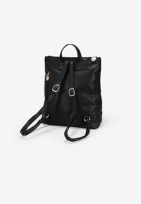 Mochila de cuero negro con dos correas ajustables, dos asas superiores y acentos en tono dorado. Presenta una superficie lisa y texturizada.