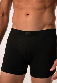 Boxers en coton noir avec une texture lisse et une ceinture élastique comportant une étiquette de logo. Design ajusté, longueur mi-cuisse.