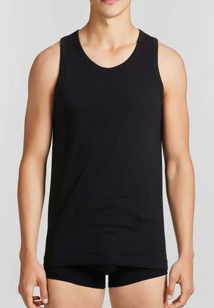 Canotta nera in cotone con scollo rotondo e spalline larghe, design aderente, texture liscia, indossata sopra pantaloncini neri.