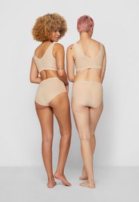 Two models wearing light beige lingerie sets, featuring seamless design, soft texture, and full coverage. Back view shows wireless bras and high-waist briefs.