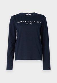 Tengerész kék, hosszú ujjú póló pamutból, fehér "TOMMY HILFIGER" logóval, alatta "EST. 1985" felirattal. Kerek nyakkivágás és lazán illeszkedő fazon.