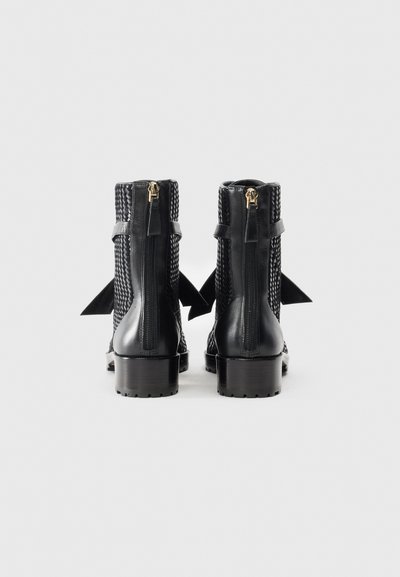 Svarta ankelstövlar med vävd struktur och slät läderbas, med dragkedja och rosett detalj baktill. Klumpig klack.