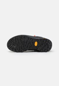 Black hiking shoe sole with textured grip pattern, featuring a bright orange accent and a distinct yellow Vibram logo. Rugged and durable design.