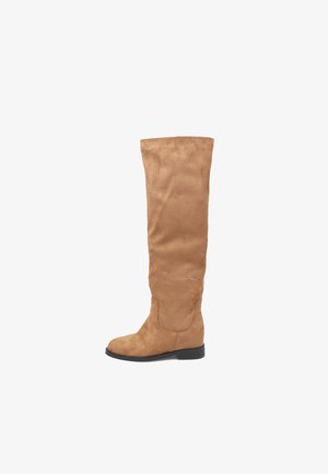 Knöchelhohe, beige Wildlederstiefel mit flacher schwarzer Sohle. Glatte Textur mit minimalen Nähten und ohne sichtbare Beschläge.
