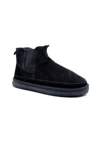 Bottines noires en daim avec des panneaux élastiques sur les côtés, un tissu texturé et une semelle en caoutchouc arborant un motif tissé distinct le long du bord.