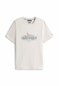 Kortærmet, cremfaret T-shirt lavet af bomuld. Har et blåt trykt logo med dekorative detaljer i midten og en rund halsudskæring.