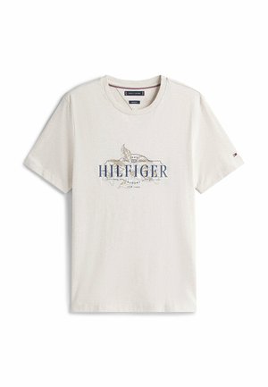 Korte mouwen, crèmekleurig T-shirt van katoen. Heeft een blauw gedrukt logo met decoratieve accenten in het midden en een ronde hals.