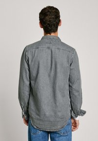 Graues Denimhemd mit einem Kragen, langen Ärmeln und geknöpften Manschetten. Verfügt über einen abgerundeten Saum und seitliche Schlitze für eine lockere Passform.