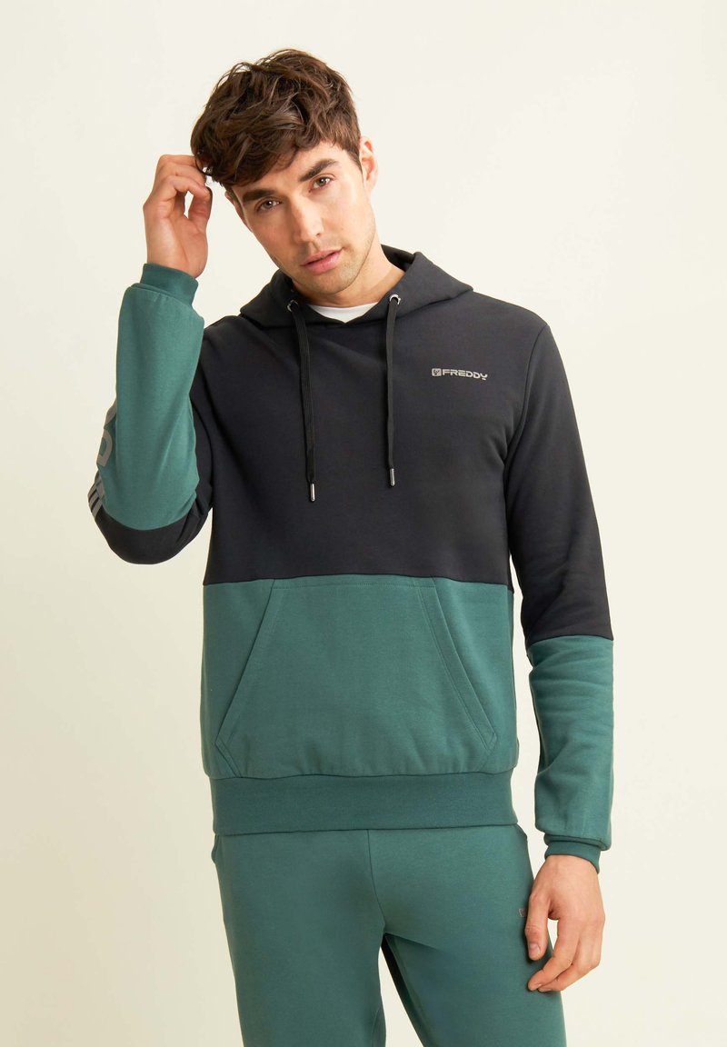 Felpa con cappuccio caratterizzata da un design a blocchi di colore in blu navy e teal. Realizzata in un tessuto confortevole, presenta una tasca a marsupio e un cappuccio con cordini.