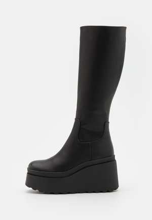 Black knee-high platform boots with a smooth leather texture, round toe, elastic side panels, and a chunky, textured sole.