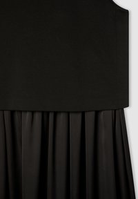 Czarna sukienka z wyraźnie zarysowaną górą, gładką, dopasowaną górą i zwiewnym, plisowanym dołem, który sięga poniżej talii.
