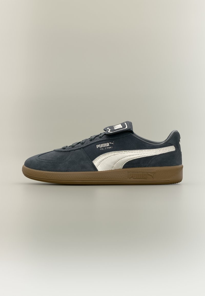 Baskets Puma Palermo noires avec une bande blanche et une semelle en gomme, vues de côté sur un fond neutre uni.