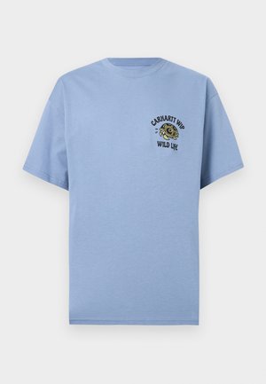 Tricou bleu deschis cu mâneci scurte, cu un mic grafic cu broască țestoasă verde și textul "Carhartt WIP Wild Life" pe pieptul stâng.