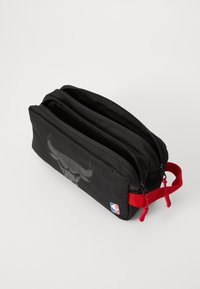 Schwarze rechteckige Tasche mit zwei Reißverschlussfächern, die ein Stierlogo auf der Vorderseite und rote Akzente an den Reißverschluss-Ziehen und dem Griff aufweist.