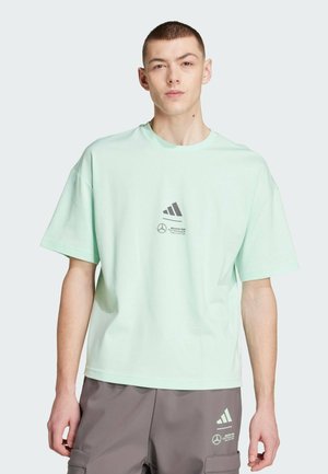 T-shirt à manches courtes vert menthe clair en coton, ornée d'un logo adidas noir imprimé et d'une marque Mercedes sur le devant.