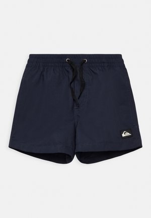 Shorts de bain bleu marine avec une taille élastique et un cordon noir. Présente une petite étiquette avec logo sur le côté gauche à l'avant.