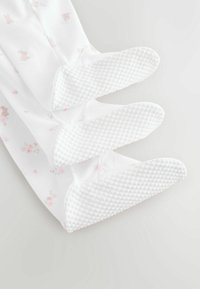 Hvide strømpebukser med kanin- og blomsterprint, med teksturerede, gummiagtige såler for greb. Blødt, strækbart stof.