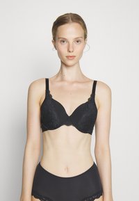 Black lace bra with molded cups, adjustable straps, and scalloped edges. Smooth texture with floral patterns and a classic design.
