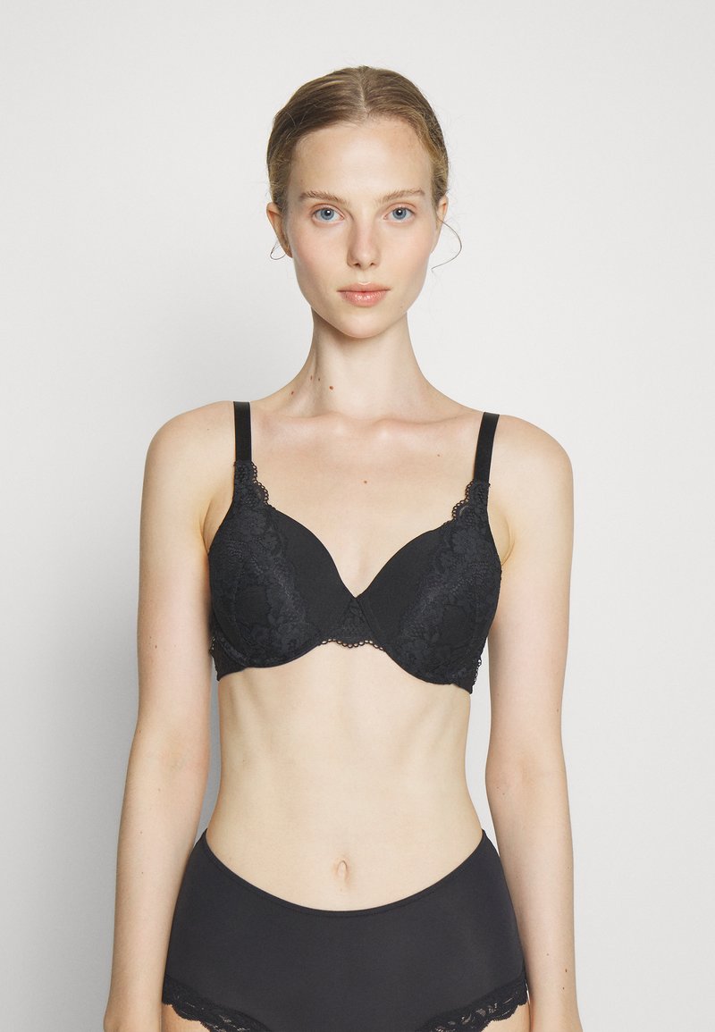 Black lace bra with molded cups, adjustable straps, and scalloped edges. Smooth texture with floral patterns and a classic design.