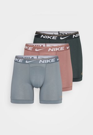 Trois paires de boxers Nike : une grise, une rouge et une vert foncé. Tissu lisse, design ajusté, ceintures contrastées avec logo.