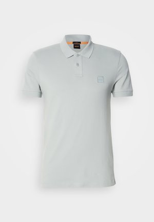 Ljusgrå polo t-shirt tillverkad av bomull, med en klassisk krage, tvåknappsslutning och en liten logopatch på bröstet. Korta ärmar.