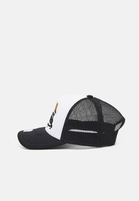 Svart og hvit trucker caps med en solid front, mesh bak, buet skygge, og en grafisk logodesign på frontpanelet.