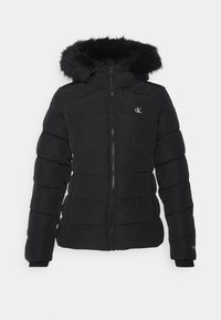 Doudoune noire avec fermeture éclair frontale, capuche doublée en fourrure, poches latérales et petit logo "cK" sur la poitrine et le poignet de la manche.