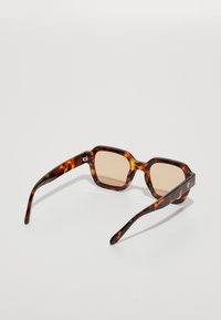 Tortoiseshell sunglasses with square frames, brown lenses, and sleek arms. Features logo detail on the side.