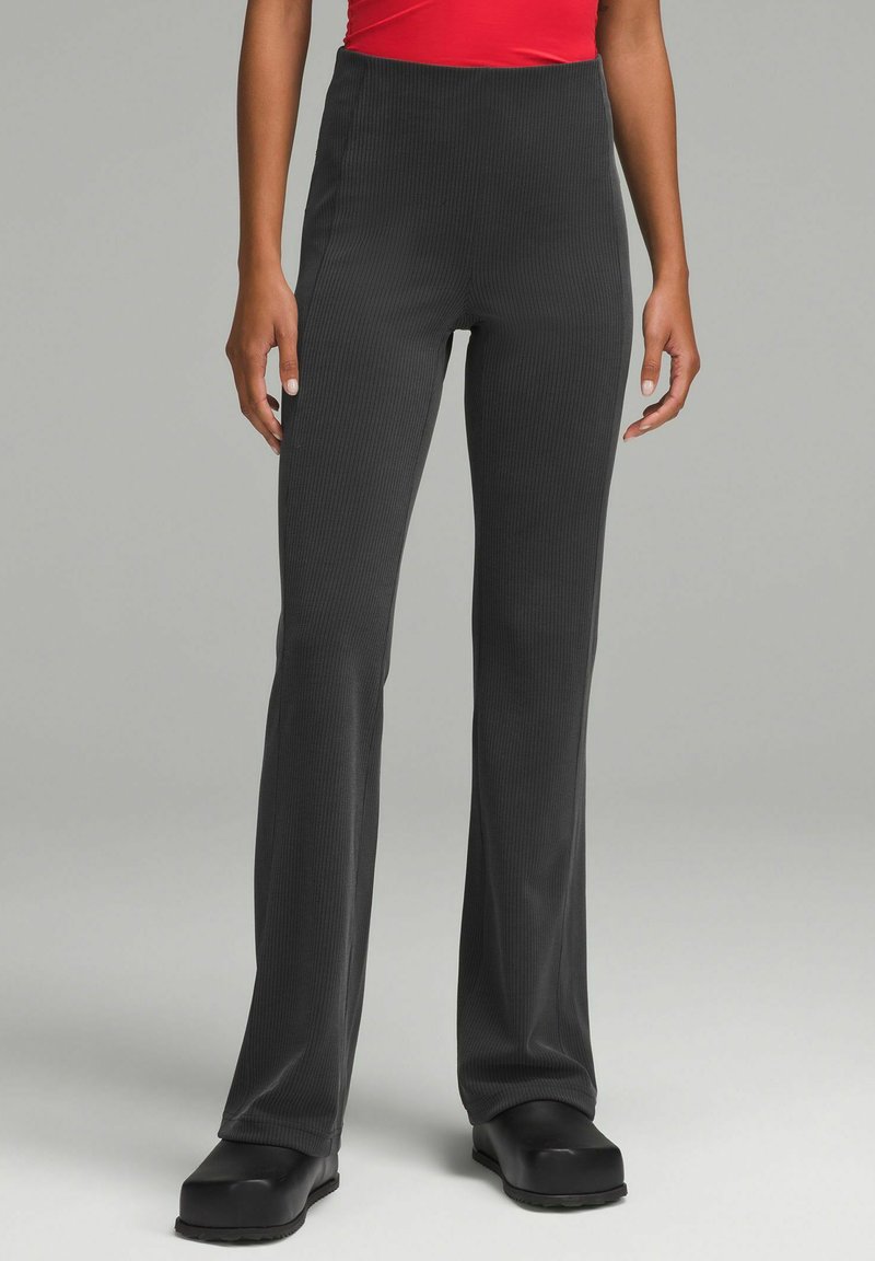 Korkeavyötäröiset, levenevät mustat housut ribbikankaasta, jossa on sileä pinta ja tiukka istuvuus lantiolla, leveällä lahkeella.