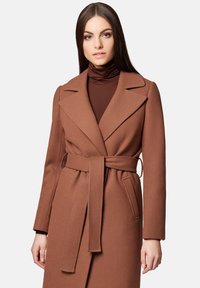 Brązowy płaszcz z szerokim kołnierzem i długimi rękawami, wykonany z teksturowanej tkaniny. Posiada duże kieszenie z przodu i przewężoną talię.
