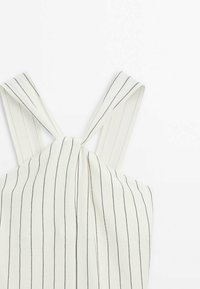 Tissu blanc avec fines rayures noires verticales, doté de larges bretelles et d'un détail de nœud torsadé au centre en haut.