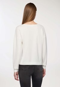 Maglione bianco a maglia con una vestibilità morbida, polsini e orlo a coste, dotato di un ampio scollo e maniche scese.