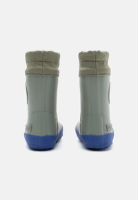 Botas de tobillo de goma verde con una suela texturizada azul y un puño doblado. Presenta un detalle de logo en el costado como acento de diseño.