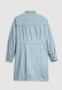 Ανοιχτό μπλε τζάκετ από τζην με μακριά μανίκια, κουμπωτές μανσέτες και πίσω λαιμόκοψη. Διαθέτει ελαφρώς φαρδύ σχέδιο και ορατές ραφές.